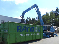 Fuchs-Bagger mit Schalengreifer an Container